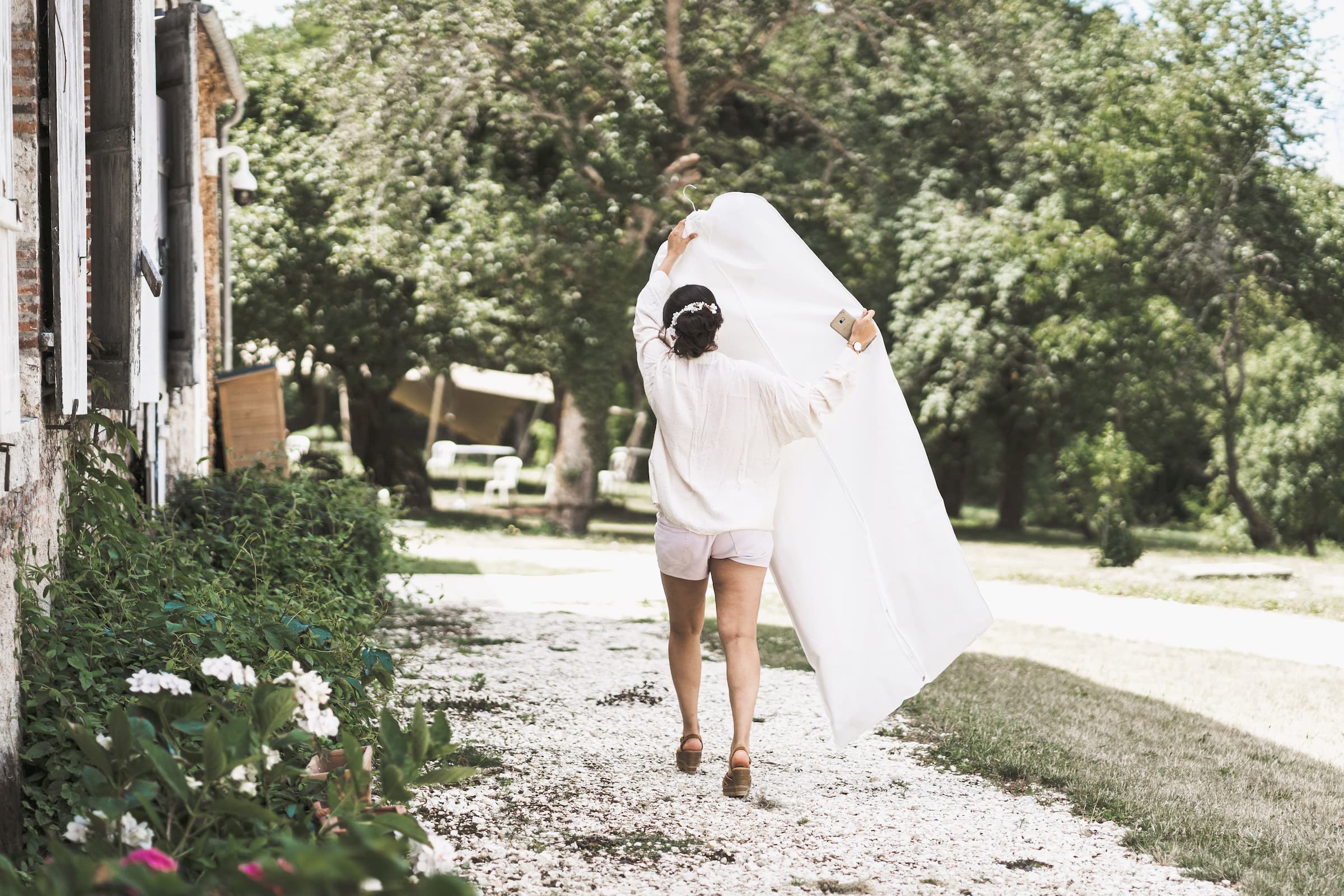 mariée portant sa robe dans une allée de jardin