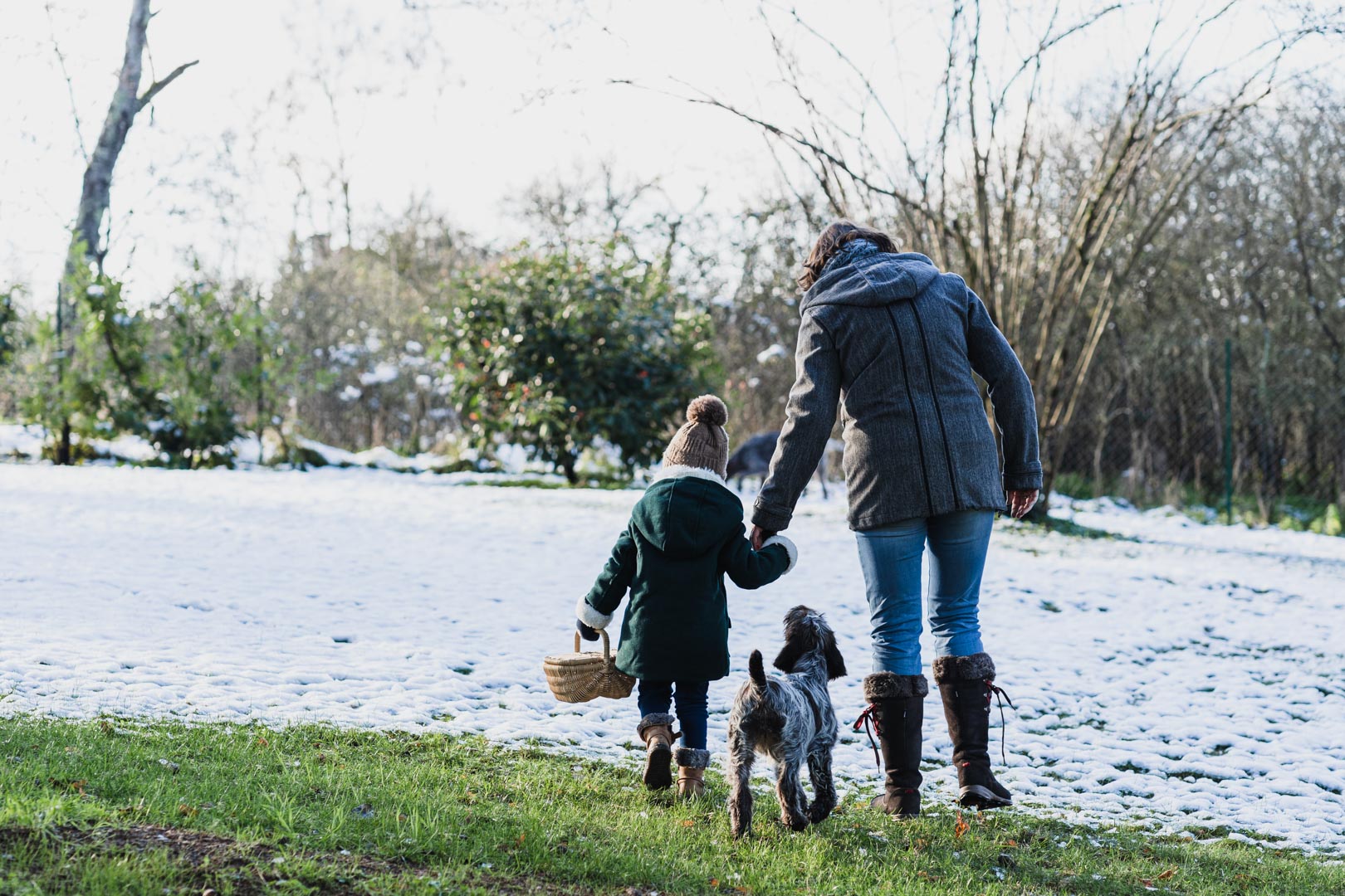 Un jeune enfant et sa maman jouent dans la neige avec leur jeune chiot durant une seance famille dans le loiret