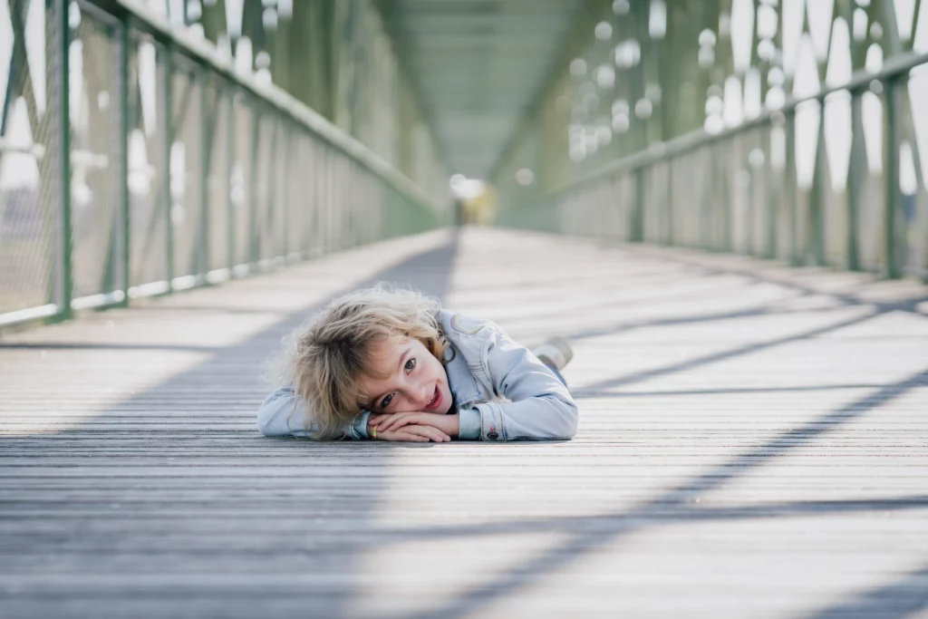 jeune fille de 4 ans couchée sur le pont piéton de saint père sur Loire dans le Loiret durant une séance photo de famille faite par christelle saffroy photographe en Normandie pres de Caen et en Région centre pres d'Orleans